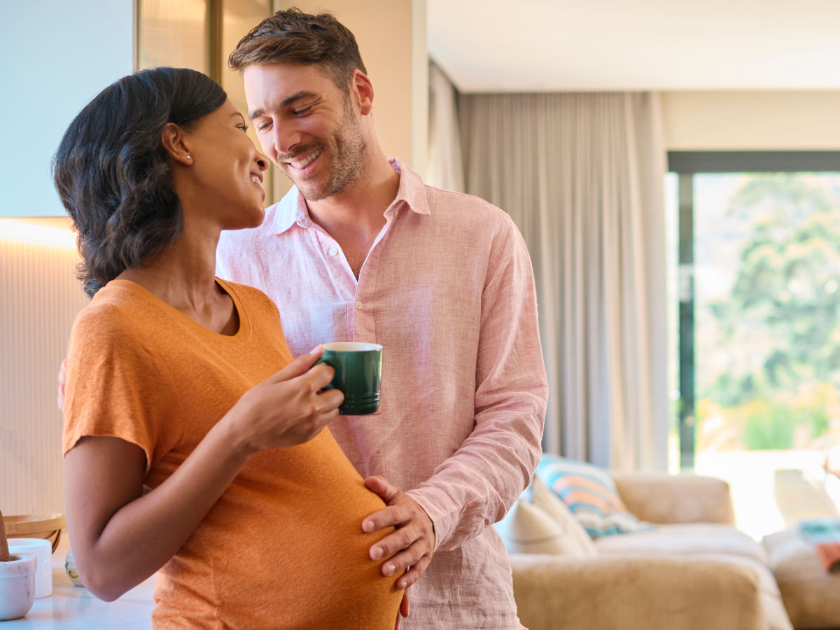 Schwangere Frau trinkt Kaffee gemeinsam mit ihrem Partner